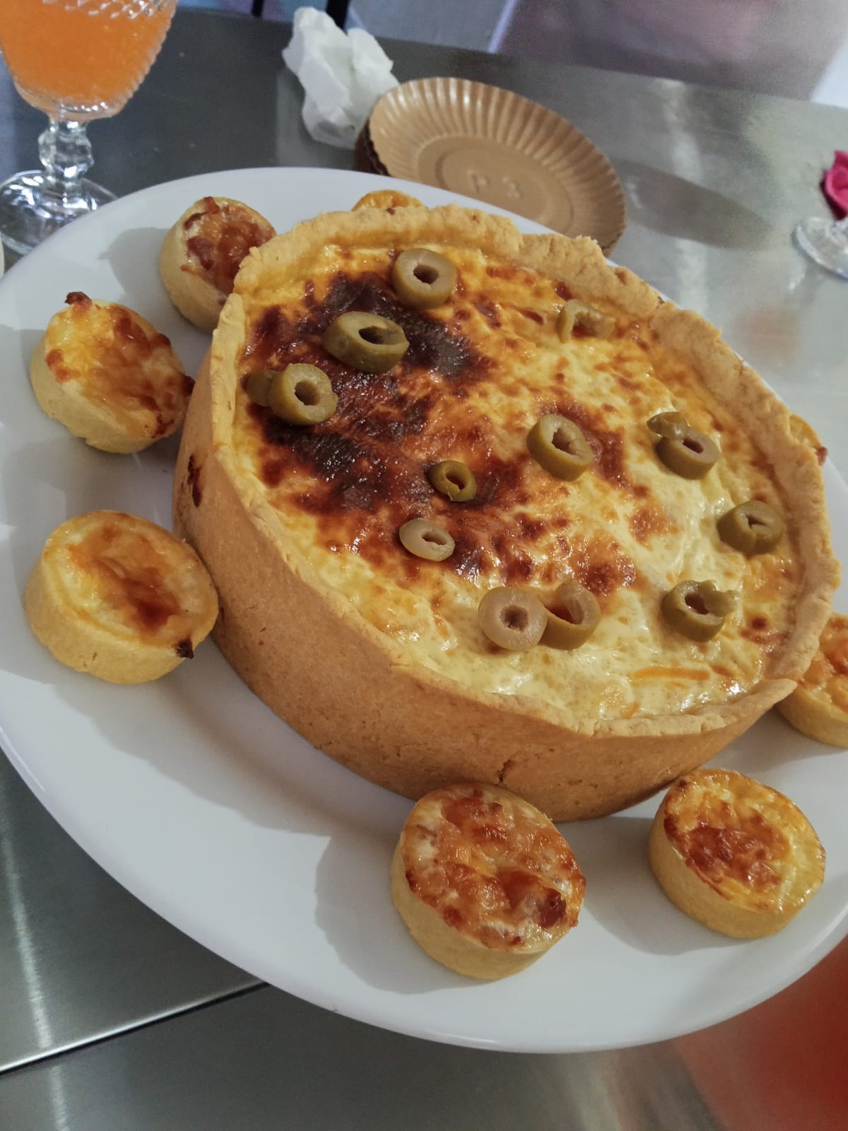 Torta salgada servida em prato branco com empadinhas ao redor